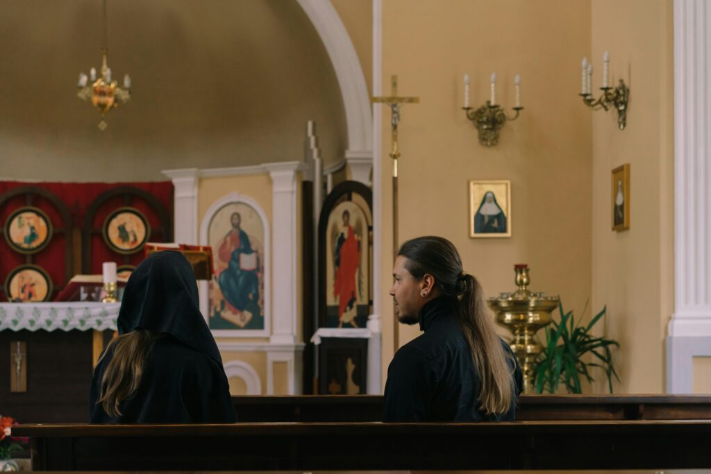 Two people sitting in church pews, showcasing a moment of religious reflection and spirituality.